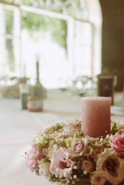 Bloemstukje met roze kaars op huwelijkstafel